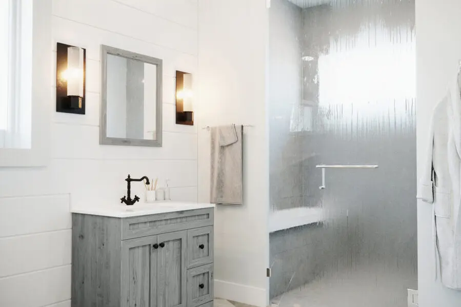 Bright bathroom with a walk-in shower, wooden vanity, and modern lighting.