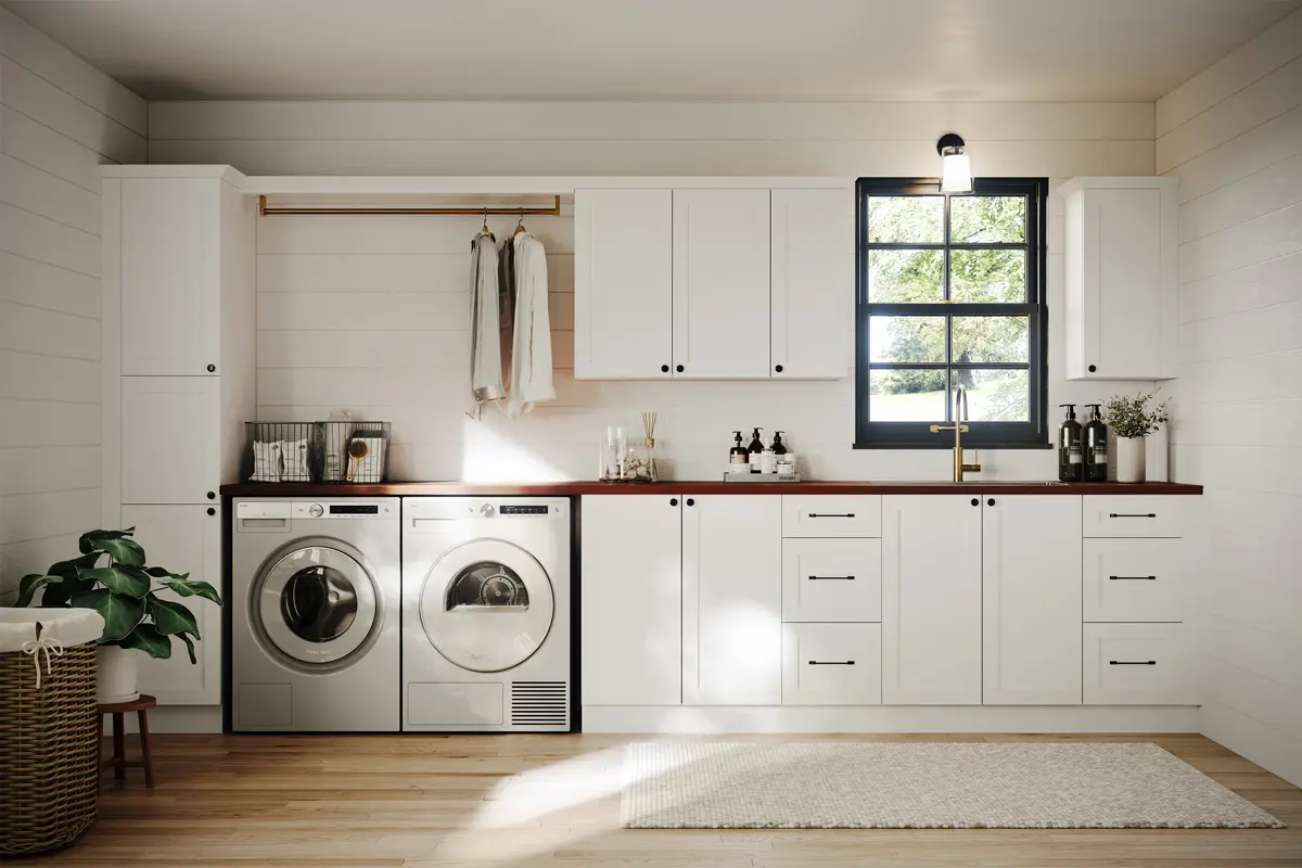 Classic white laundry room with functional storage cabinets, a farmhouse sink, and bright natural lighting.