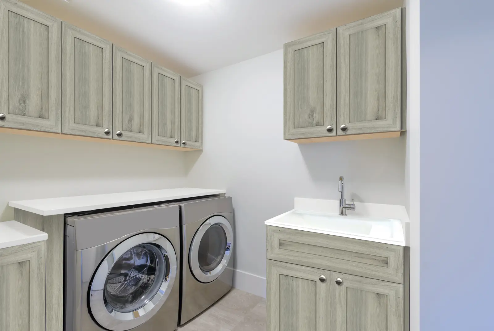 Minimalistic laundry room with wood cabinets, large counter space, and modern appliances.