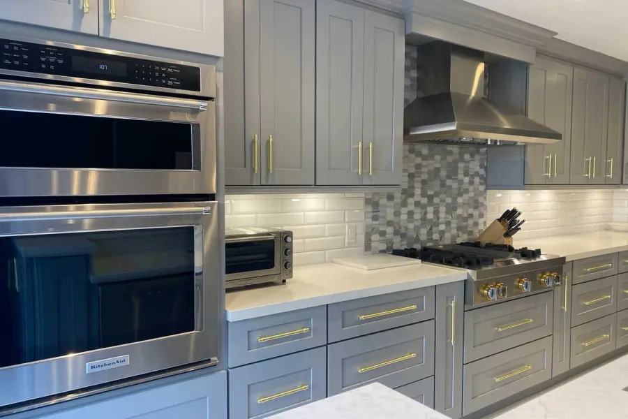 Modern kitchen cabinets in a sleek gray finish with gold hardware and integrated appliances.